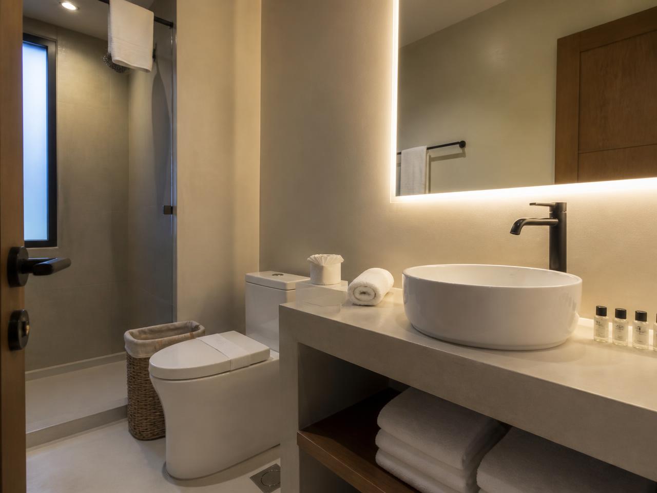 Baño de apartamento turístico limpio con lavabo, toallas enrolladas y amenities colocados